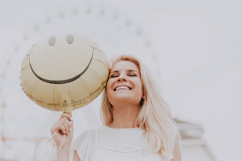 Woman holding a balloon with a smiley face